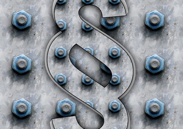 Symbolbild: ein Paragraf auf einer Wand voller Schrauben mit Muttern symbolisiert die Festlegung einer neuen gesetzlichen Regelung