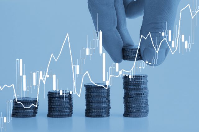 Symbolbild: wachsende Geldstapel mit einer Hand, die den rechten Stapel weiter erhöht. Darüber Grafen, die die Entwicklung der Investitionen darstellen.