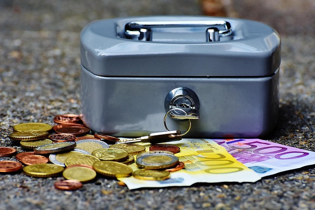 Symbolbild: Eine abschließbare Kasse aus Metall und Geldscheine und Münzen davor symbolisieren die Kassensicherungsverordnung
