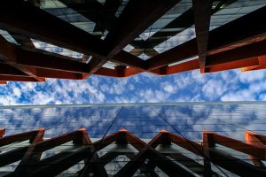 Symbolbild: Eng beieinander stehende moderne Glas-Stahl-Fassaden mit Blick zum Himmel symbolisieren Banken mit hohen Eigenmitteln.