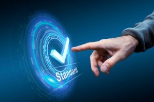 Symbolbold: eine Grafik in verschiedenen Blautönen stellt ein Rad dar mit einem Haken und dem Wort "Standard" darunter - symbolische für den neuen IDW Prüfungsstandard.