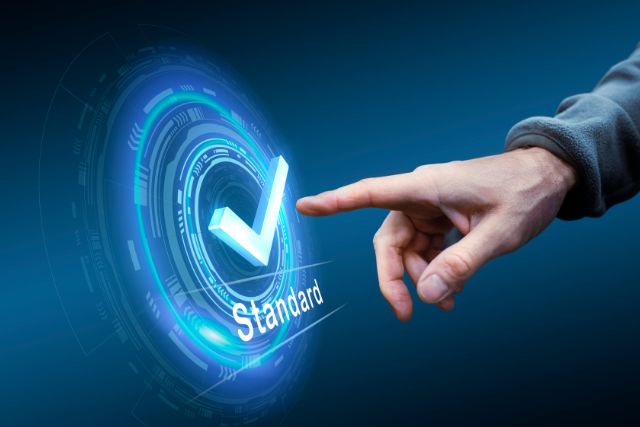 Symbolbold: eine Grafik in verschiedenen Blautönen stellt ein Rad dar mit einem Haken und dem Wort "Standard" darunter - symbolische für den neuen IDW Prüfungsstandard.